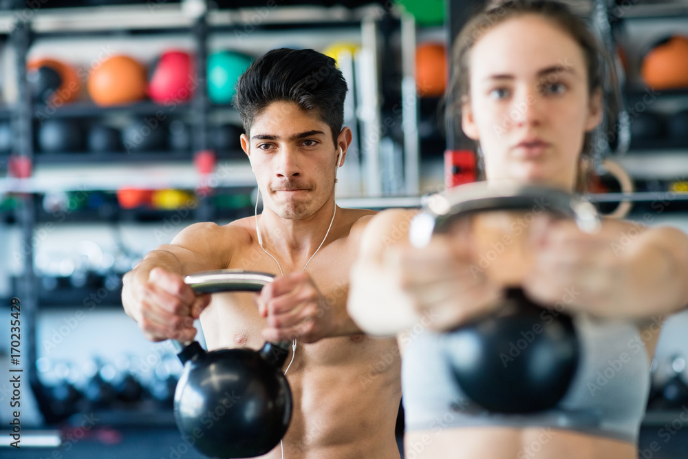 Young fit couple in gym exercising with kettlebell. Young fit couple in gym exercising with kettlebell.