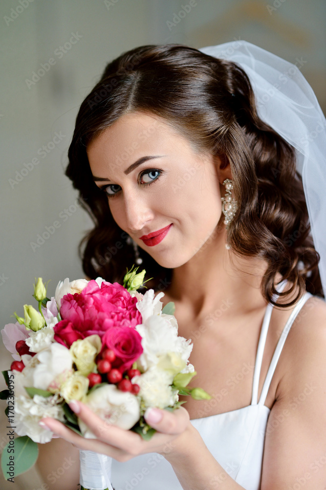 Beauty bride in bridal gown with bouquet and lace veil indoors Beauty bride in bridal gown with bouquet and lace veil indoors