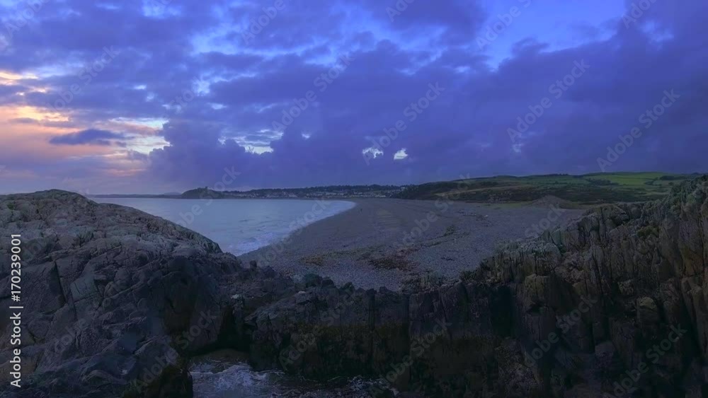 Establishing rising aerial shot over a beach in Porthmadog in Wales, looking out towards Criccieth. Establishing rising aerial shot over a beach in Porthmadog in Wales, looking out towards Criccieth.