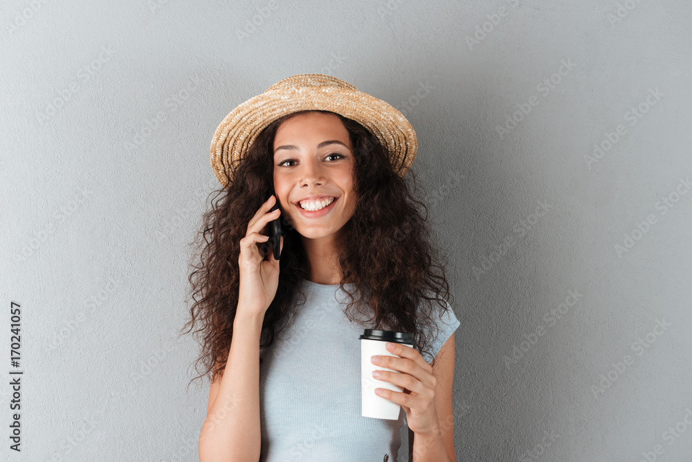 Beauty smiling curly woman in hat talking by the smartphone Beauty smiling curly woman in hat talking by the smartphone