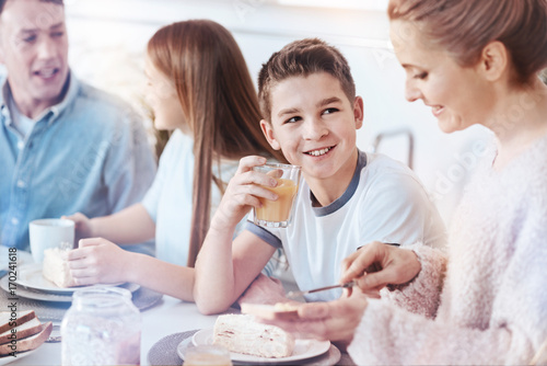 Smiling little boy enjoying orange juice during family breakfast