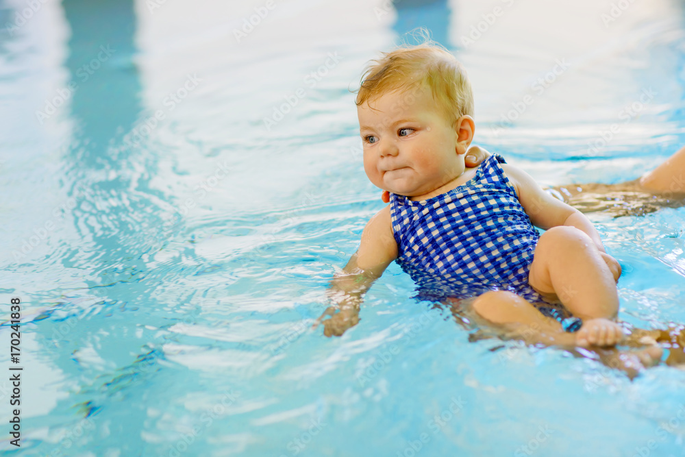 Cute little baby child learning to swim in an indoor pool Cute little baby child learning to swim in an indoor pool