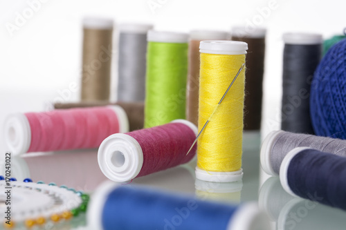 Sewing equipment and threads on white background.