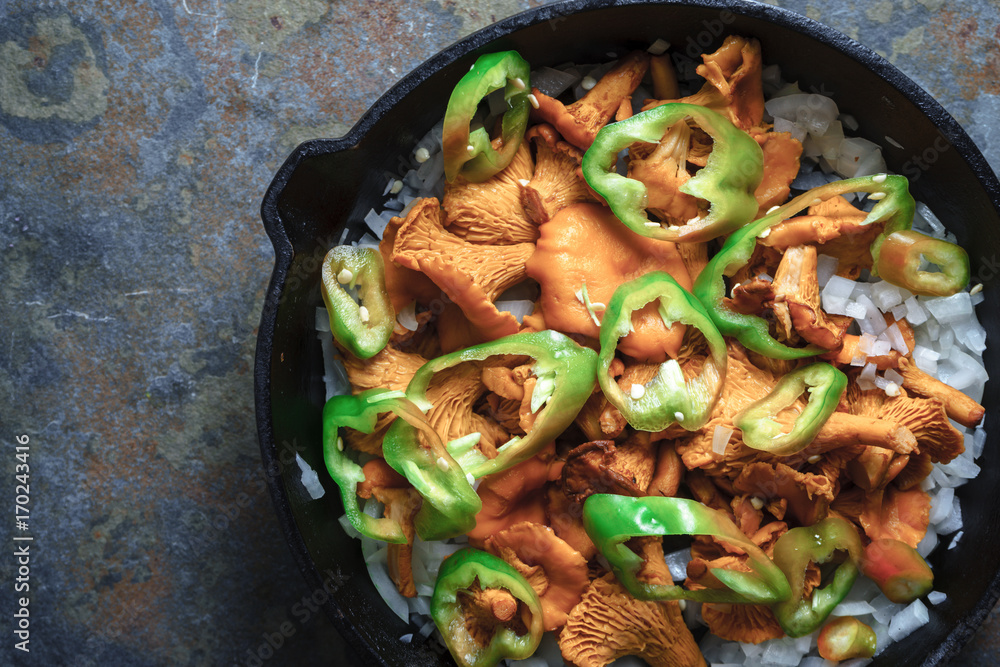 Mushrooms chanterelles, onion and pepper in a frying pan close-up Mushrooms chanterelles, onion and pepper in a frying pan close-up