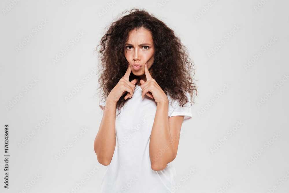 Calm curly woman folding fingers on cheeks Calm curly woman folding fingers on cheeks