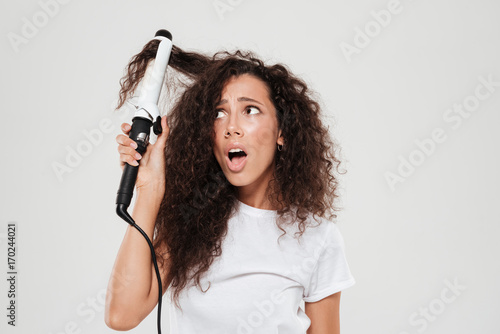 Surprised young brunette woman straighten her hair