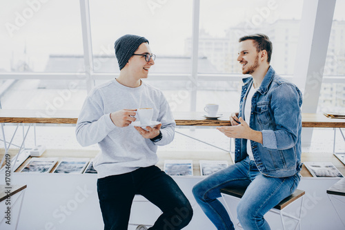 Men are sitting in front of the table near window