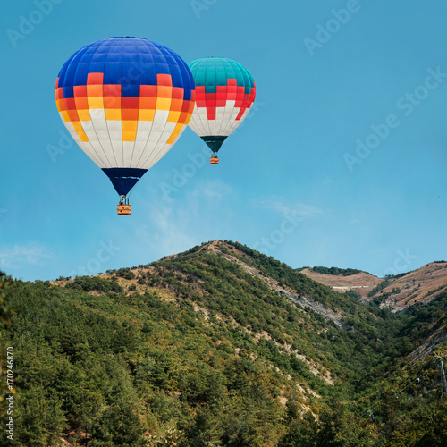 Colorful hot-air balloons flying over the mountains against blue sky