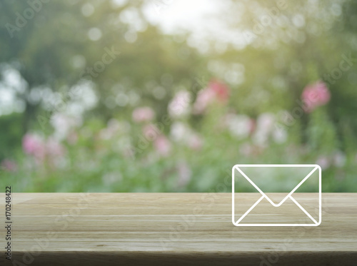 Mail icon on wooden table over blur pink flower and tree, Contact us concept