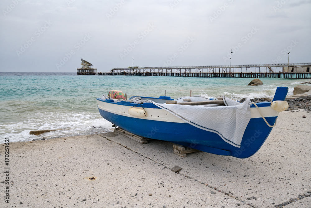 Disembarked blue boat in front of an abandoned shipping pier Disembarked blue boat in front of an abandoned shipping pier
