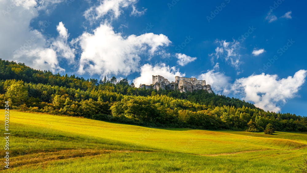 The ruins of a medieval castle Lietava on a rocky blade over a wooded landscape and grassy meadows, nearby Zilina town, Slovakia, Europe.