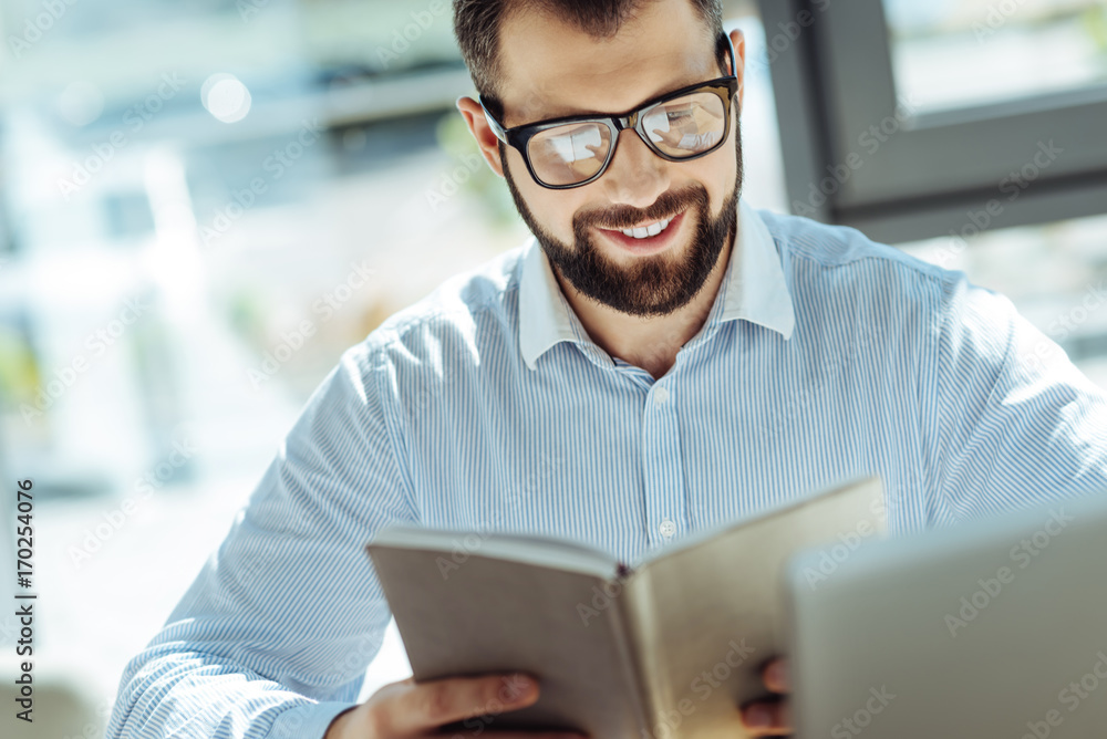 Pleasant man looking through his notes in notebook Pleasant man looking through his notes in notebook