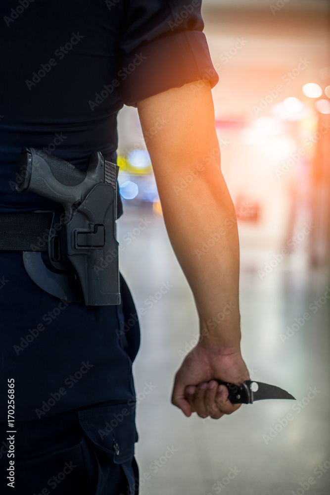 Rear view of man holding a knife in his hand and carry a gun weapon in holstered at the waist.