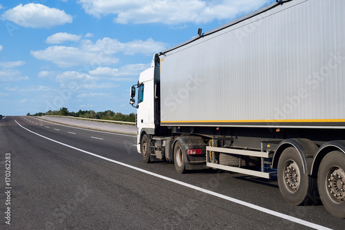 Truck on road with container and cloudy sky, cargo transportation concept