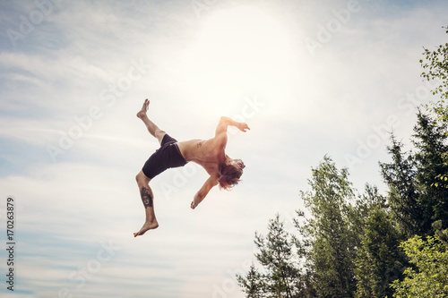 Young man doing a backflip in the air.