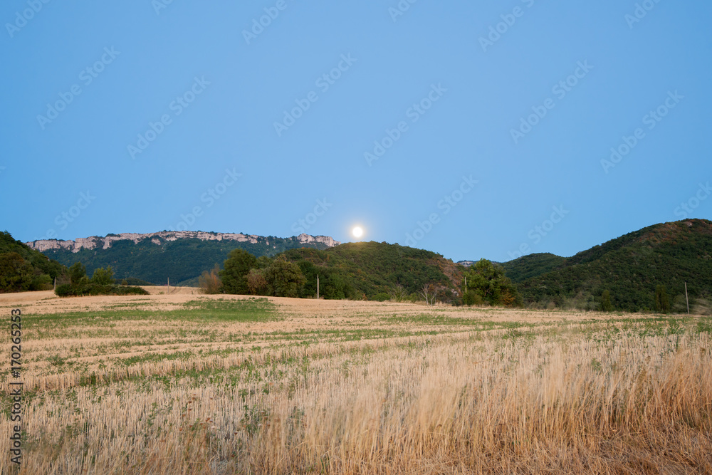 Nice view over the mountains and fields in the hills underneath an emerging moon