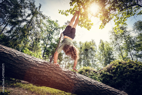 Tablou canvas Young man doing a handstand on a tree trunk in the forest.