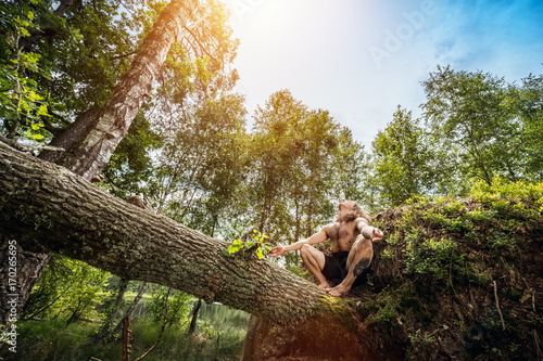 Young man sitting on a tree trunk in the forest. © Photocreo Bednarek