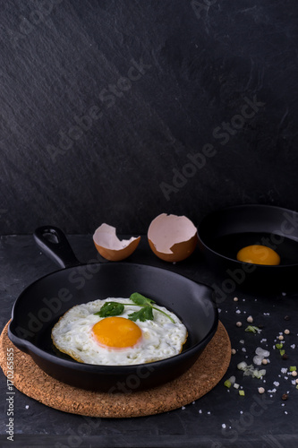 fried egg in black pan and ingredient on dark background