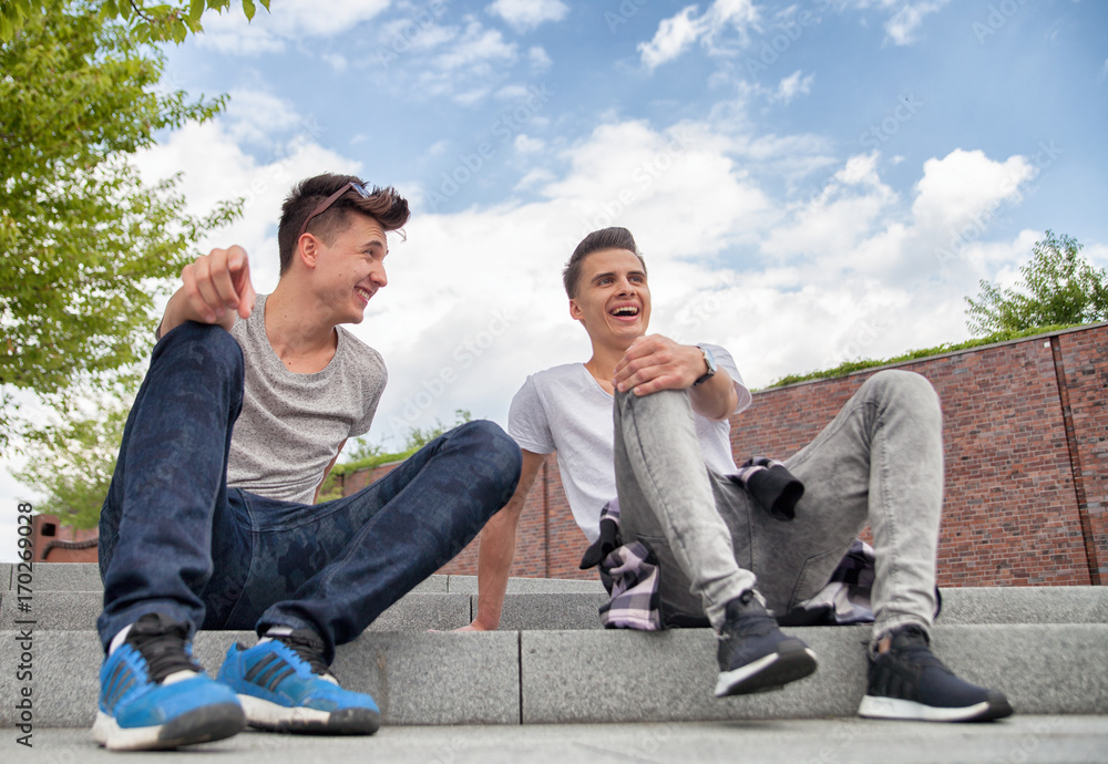 Two friends sitting on stairs in town and laughing, best friend concept
