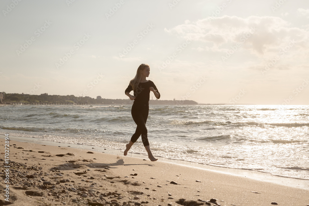 sports female silhouette running at sunny sea beach