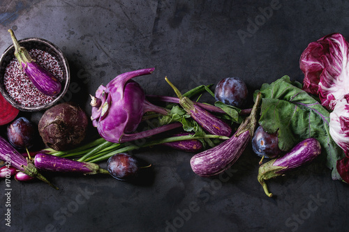 Assortment raw organic of purple vegetables mini eggplants, spring onion, beetroot, radicchio salad, plums, kohlrabi, flower salt over dark metal background. Top view with space