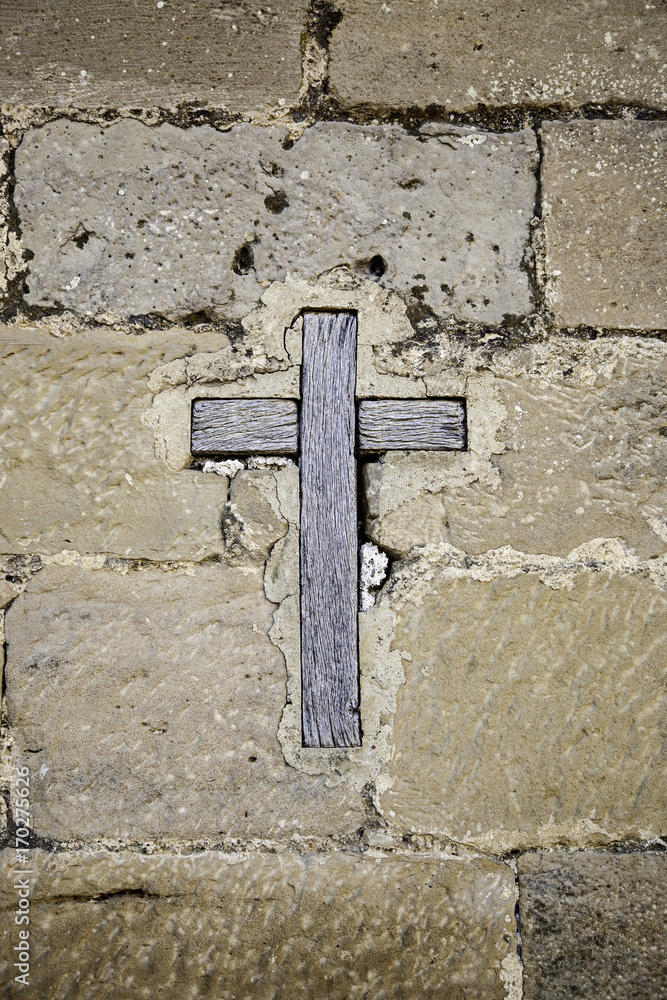 Medieval wooden cross on a stone wall