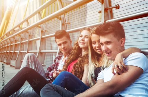 Group of friends sitting together outdoor on urban scenery