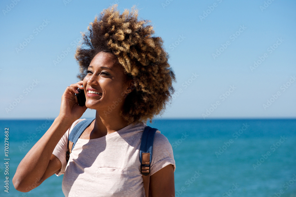 Fototapeta premium Close up beautiful african woman talking on mobile phone by the sea