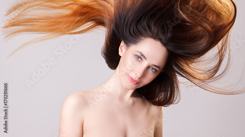 Beautiful model girl with shiny flying brown ombre straight long hair . Care and hair products .