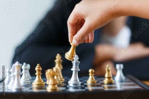 Close up shot hand of child moving golden chess to defeat and kill silver king chess on white and black chess board for business challenge competition winner and loser concept