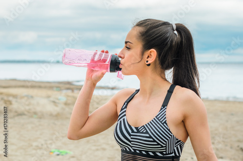Girl beautiful brunette. Athletic body , pumped muscles. Bright colors , green ,pink . Spring , trees in bloom. She does a workout on the beach. Rides a Bicycle . makes a selfie