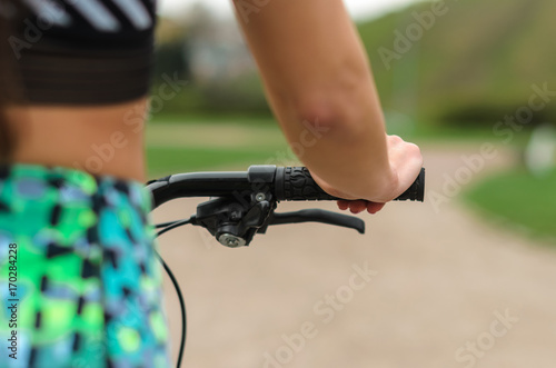 the girl the brunette in sportswear, rides a bike in the morning in the park. Close up