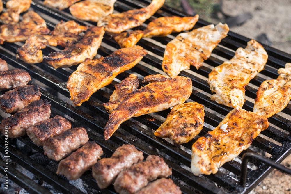 Flat lay above chicken white breast meat on the barbecue grill with kebabs