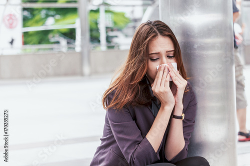 Sick business woman with sneezing in tissue