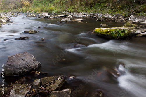 River in the forest with stones. Silk water.