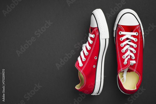 Pair of red classical gymshoes isolated on dark background photo