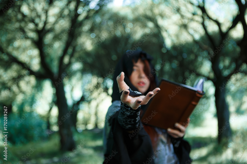 Photo of witch with outstretched hand and book Photo of witch with outstretched hand and book
