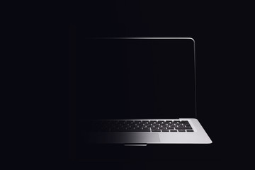 Portable modern silver computer on a black background. Half the computer in the shade.