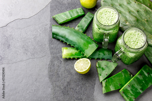 Healthy cactus nopales, aloe vera and lemon detox drink in jars and ingredients on gray background. Top view
