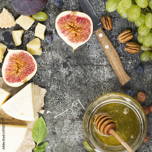 Cheese board for snacks, tricks, meetings with friends, on a gray stone background: assorted cheeses, young cheese, parmesan, cheese with fenugreek, figs, nuts, honey, grapes Top View. photo