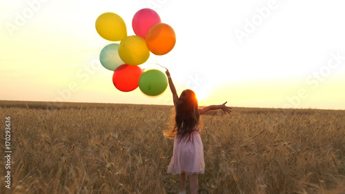 girl walking in a field with balloons