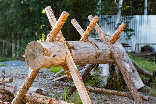 wooden device for cutting firewood and the stack of wooden logs near the wooden fence photo