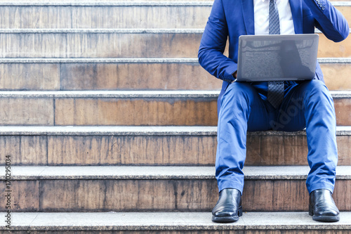 Businessman sitting on stairs and using laptop © Art_Photo