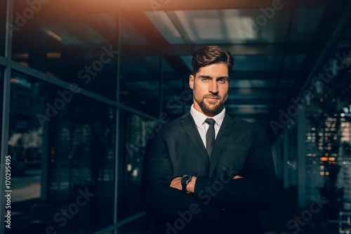 Handsome young businessman standing with his arms crossed