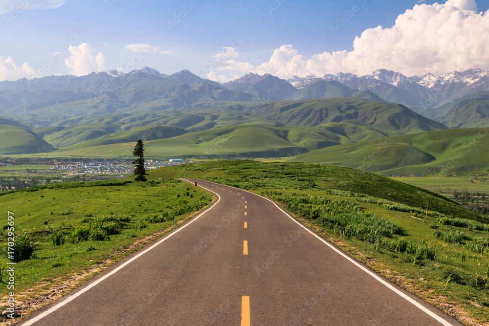 Naklejka premium road through grasslands and mountains