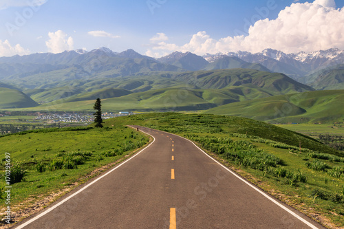 road through grasslands and mountains photo