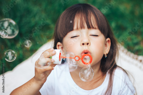 little girl blowing bubble to camera close up