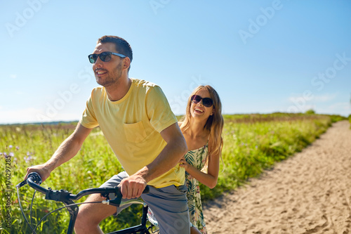 happy couple riding bicycle together in summer