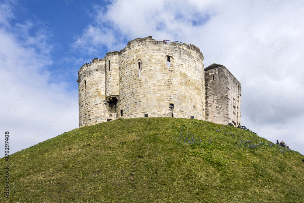 wide angle shot of the York Castle - Cliffords Tower - against a deep blue sky and volumetric clouds, Yorkshire, England, UK
